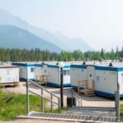 Neighbourhood of trailers surrounded by a forest of trees and mountains.
