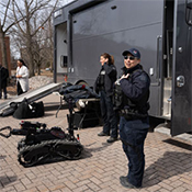 A CBRNE team demonstrates a bomb disposal robot outdoors beside an operations truck.