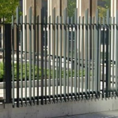 Figure depicting a fence with vertical metal fencing bars extend passed concrete wall