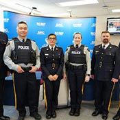 6 RCMP police officers facing the camera in front of an RCMP Central Region backdrop.