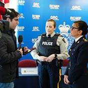 2 RCMP police officers answering questions from a journalist, with a television camera with the CBC logo on it in the foreground.