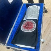A wider perspective of a small white blanket covering the top of a trophy lying in a blue-lined case.