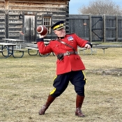An officer in Red Serge is seen throwing a football.