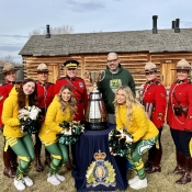 Five officers in Red Serge pose with the three Edmonton Elks Cheerleaders and the Grey Cup.