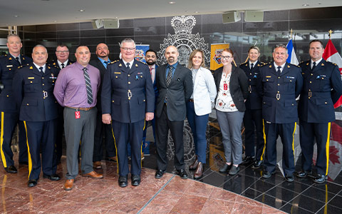 A group of police officers, some in uniform and some in business attire, pose for the camera.