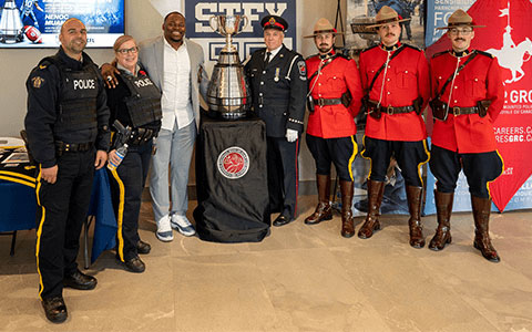 Several people, including five RCMP officers, flanking the Grey Cup.