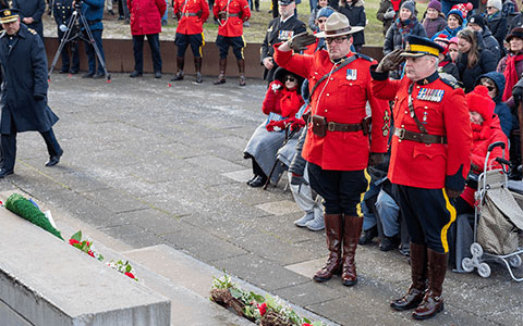 Two RCMP officers in red serge saluting.