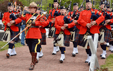 Members of the RCMP pipe and drum band walking in a parade and piping.