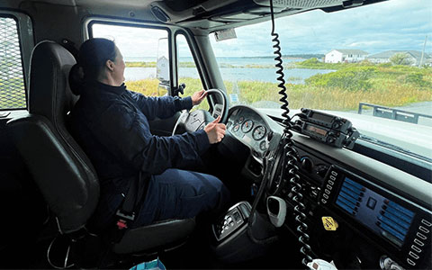 An RCMP officer sitting behind the wheel of a large RCMP vehicle.