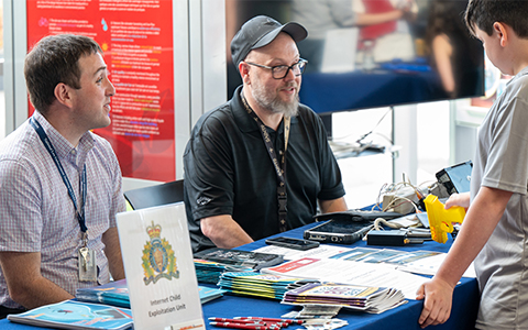 A youth visits a display table set up by two members of the Internet Child Exploitation Unit.