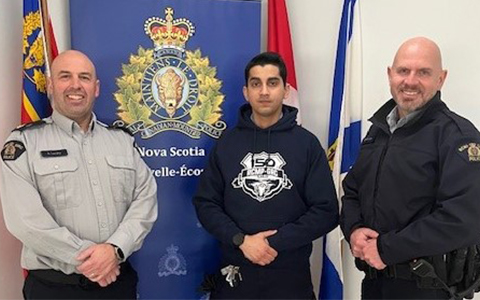 Two RCMP officers stand on each side of a candidate in the Diverse and Inclusive Pre-Cadet Experience program.