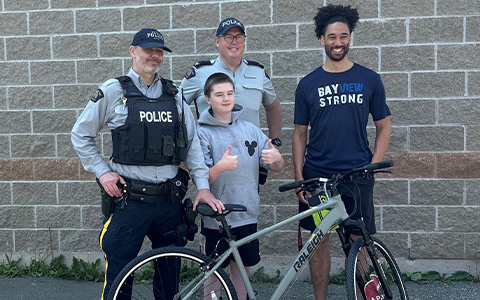 Four people, including a child and two police officers, stand behind a bike.
