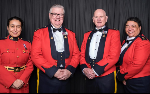 Four officers pose for a photo in red serge.