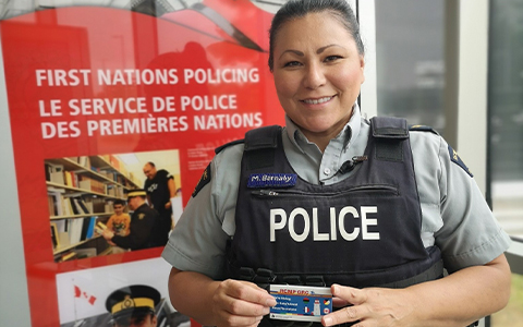 An RCMP officer shows off a trilingual recruitment card.