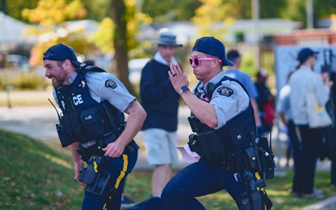 Two RCMP officers in full gear are shown running.