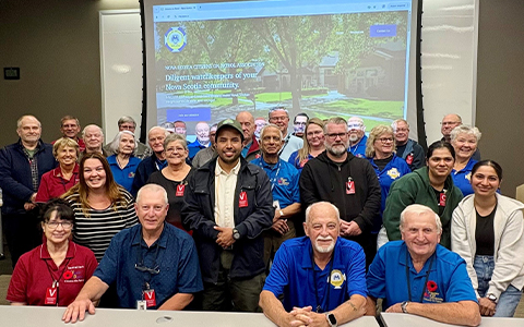 A group of people pose in front of a presentation screen.