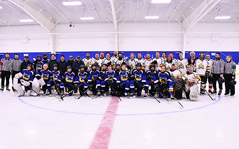 Two hockey teams and officials pose for a photo on the ice.