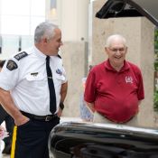 A uniformed RCMP officer and an elderly man in a red shirt