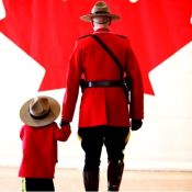 A member in red serge is seen walking with a child in red serge.