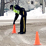 A cadet places traffic cones at the scene of a staged vehicle collision.