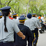 A group of cadets march behind a column of motorcycles during a parade.