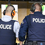 A firearms instructor helps a cadet.