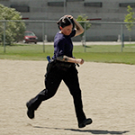 A cadet runs outside carrying a weighted object over her shoulder.