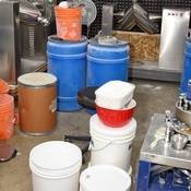 Photo of a pill press lab with mixing machines, drug powder precursor chemicals, pill pressers, and finished counterfeit pills