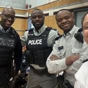 Cst. Dwight Martin stands smiling beside three other police officers in a school gym during a Black Excellence Day event at Cloverdale Traditional School (Left to right: Cst. Dwight Martin, Cpl. George Amoako, Cst. Berthier Kyobela, and Insp. Veronica Fox)