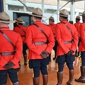 A photo of the backs several RCMP members wearing Red Serge indoors