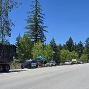An empty street with several trucks and police cars parked on either side of the road.