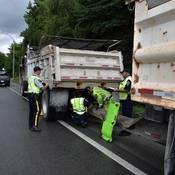 RCMP working with CVSE officers to examine a dump-truck and trailer. The truck had a hole in the bed that leaked debris onto the road