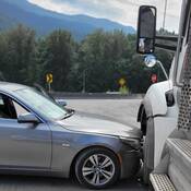 A close-up of a grey BMW sedan that collided with a white dump truck