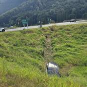 A BC Highway Patrol vehicle overlooking three people sitting by the side of Highway #1 with their Mazda SUV down an embankment
