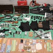 File # 2025-2451<br />
Seized items including firearms, ammunition, magazines, body armour, cash and other stolen property laid out on the floor.