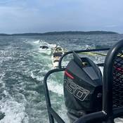 Photo of empty kayaks being towed behind RCMP boat.