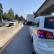 A busy roadway with two police vehicles and a commercial vehicle being inspected.