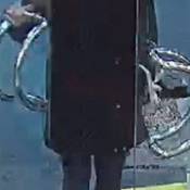 Surveillance image of Ashley Bosma from the front door of a business. She is wearing a jacket with her hood up, black tights, and bright white shoes.