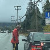 A Royal Canadian Mounted Police officer in red serge conducting a roadside stop with a vehicle