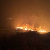 The St. Mary’s Bay Fisheries Inc. fish plant seen at night with flames and billows of smoke emerging from the structure.