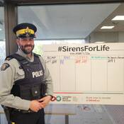 An RCMP NL officer stands next to a scoreboard at the Sirens for Life blood drive.