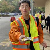 Richmond RCMP volunteer wearing a safety vest and holding a pedestrian safety reflector