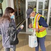 Richmond RCMP volunteer wearing a safety vest and handing out a pedestrian safety reflector to a woman