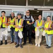 Richmond RCMP officer standing with volunteers holding pedestrian safety reflectors