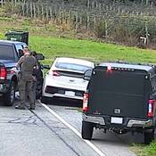 Two black unmarked RCMP vehicles and a white Hyundai ION driven by one of the suspects. Two RCMP Border Integrity officers can be seen with two individuals under arrest.