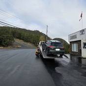 a green sport utility vehicle is loaded onto the bed of a tow truck