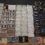 An aerial view of a table with 97 kg of illicit drugs, including Methamphetamine, Cocaine, Fentanyl and Cannabis, along with $70,000 in Canadian currency and jewelry.