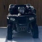An image of the stolen ATV, viewed from the front and parked in front of wooden fence in the snow.
