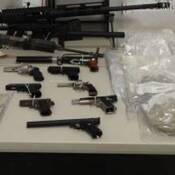 Photo of Firearms, cash, and illicit drugs seized during search warrants at Surrey and Richmond properties on a table.
