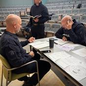 Officers work together to gather and review information while negotiations with the suspect unfold during the training scenario
